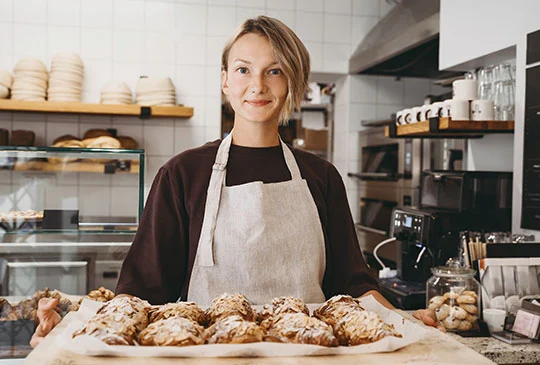 Caféanställd visar upp bakverk