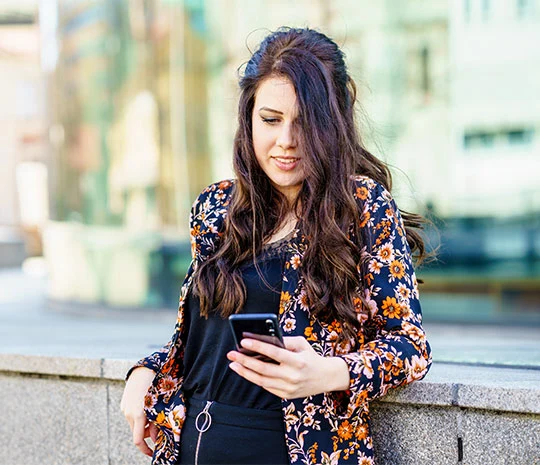 Kvinna i blommig kavaj jämför i sin mobil