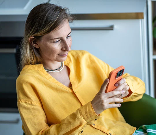 Kvinna i gul skjorta jämför lån utan UC på mobilen