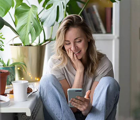 Kvinna sitter på stol och samlar lån i mobilen