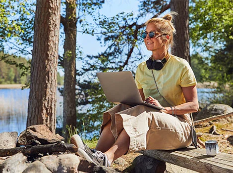 Kvinna vid sjö jämför SMS-lån på laptop