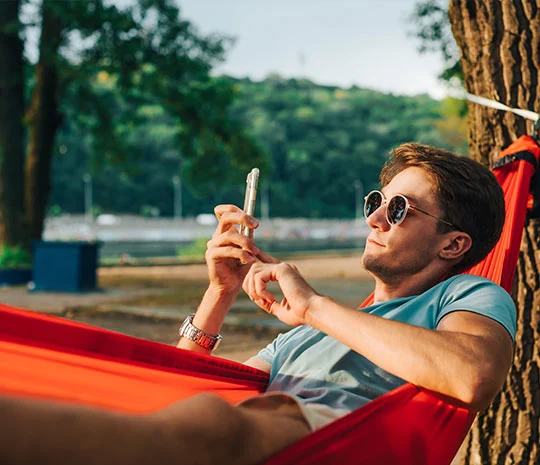 Man ligger i hängmatta och jämför lån i mobilen