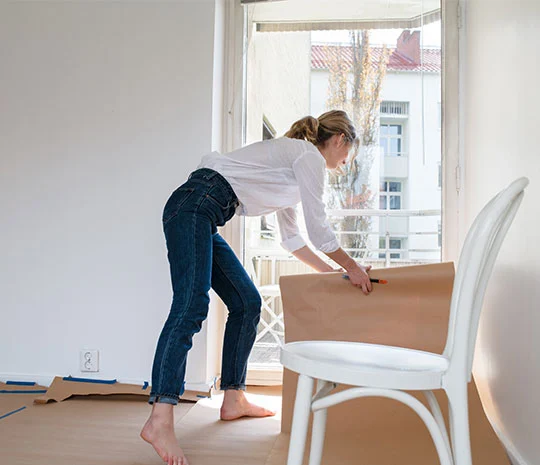 Medelålders kvinna lägger papp för att renovera sin lägenhet