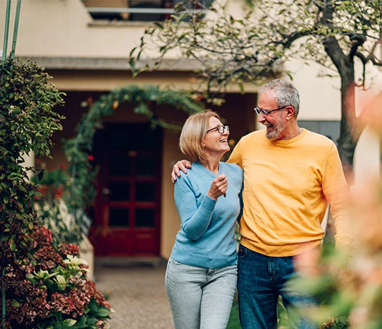 Äldre par håller nycklar och står utanför sitt nya hem