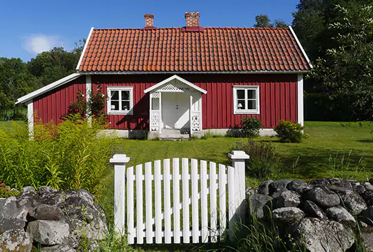 Röd sommarstuga med vitt staket