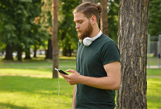 Skäggig man i grön tröja jämför SMS-lån på mobilen