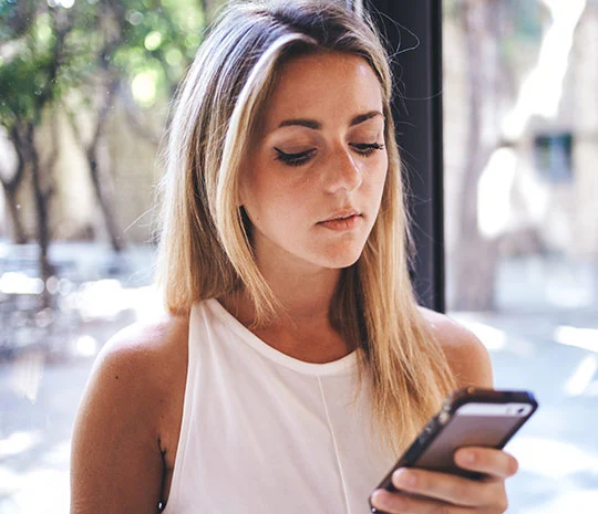 Blond kvinna utforskar SMS-lån på mobilen